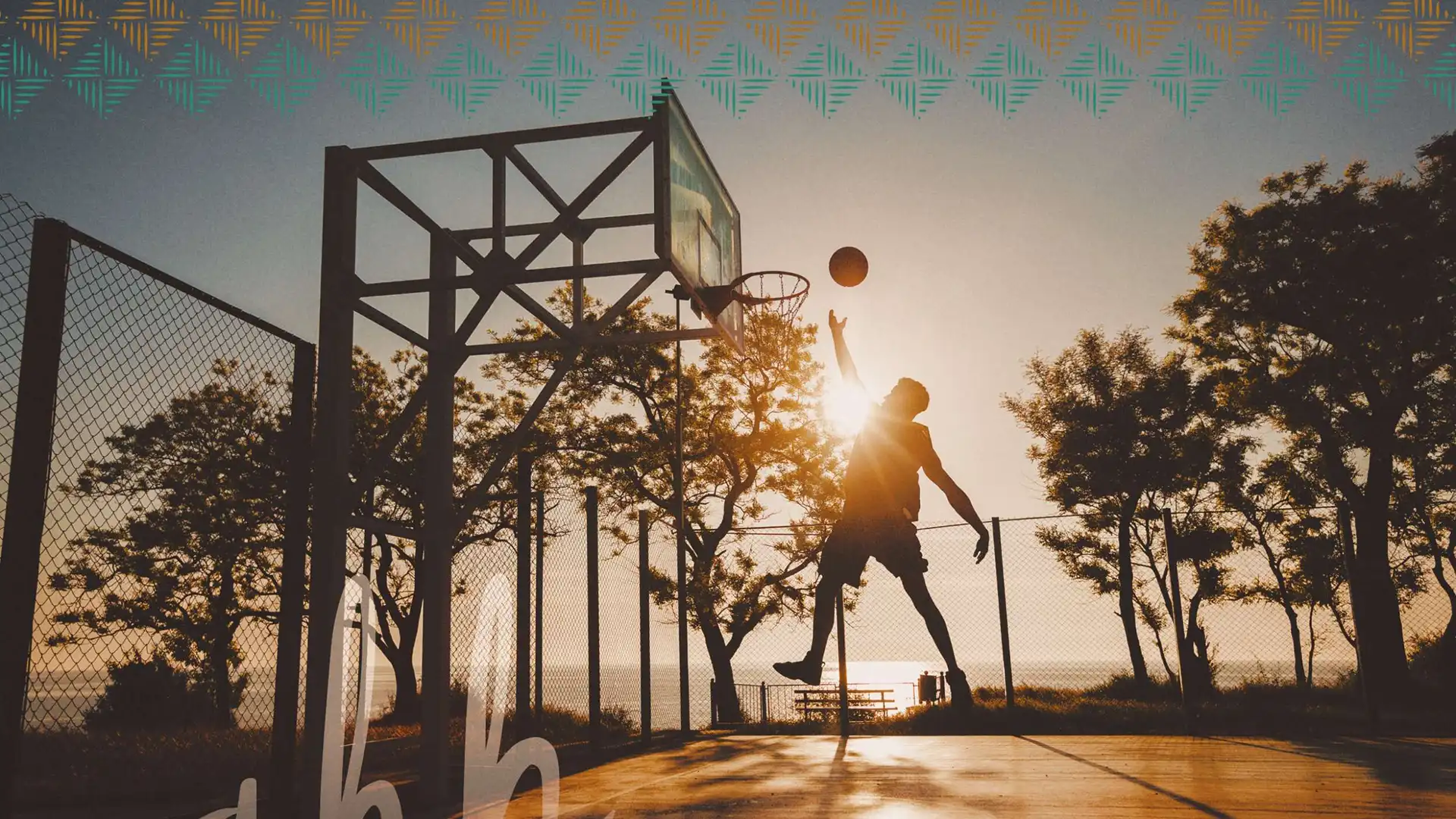 A man dunks on a basketball court at sunset